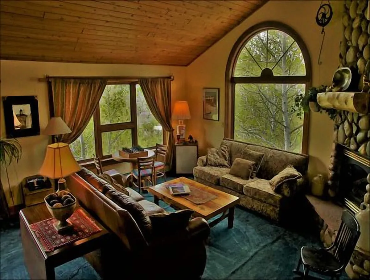 This image captures a warm and inviting living room featuring a large arched window that brings in natural light, a prominent fireplace, a comfortable sofa, coffee table, and a decorative lamp. The setup suggests a cozy space perfect for relaxing, socializing, or enjoying a warm drink by the fire.